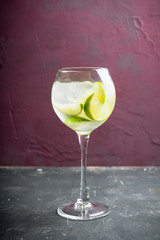 Rum based cocktail with lime in wine glass (variation of cuba libre) on the rustic background. Selective focus. Shallow depth of field.