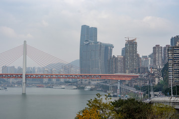 Fototapeta na wymiar Qian si men suspension bridge with sky scrapers in background by Yangtze river in Chongqing, China