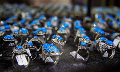 Row of rings with blue stone on the shelf of jewerely store