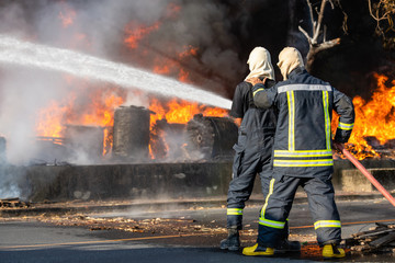 Firefighter spraying water from big water hose to prevent fire