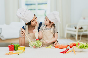 Happy family mom teaching cute girl preparing and cooking healthy salad for the first time. first lesson and healthy lifestyle concept.