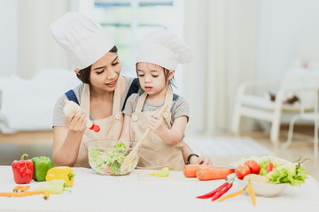 Happy family mom teaching cute girl preparing and cooking healthy salad for the first time. first lesson and healthy lifestyle concept.