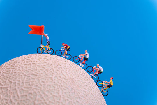 Miniature toys - road cyclist approaching finish line, celebration concept.