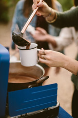 woman pouring hot chocolate into a camping mug outdoors