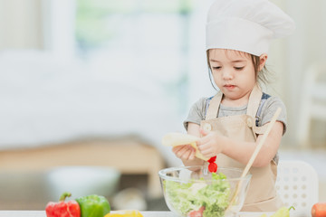 Sweet little cute girl is learning how to make a salad, in the home kitchen, Family concept, Vintage color tone.