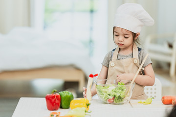 Sweet little cute girl is learning how to make a salad, in the home kitchen, Family concept, Vintage color tone.