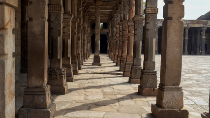 looking along a colonnade at qutub minar ruins in delhi