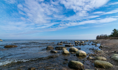 Fototapeta na wymiar blue seascape with many stones on a sunny day