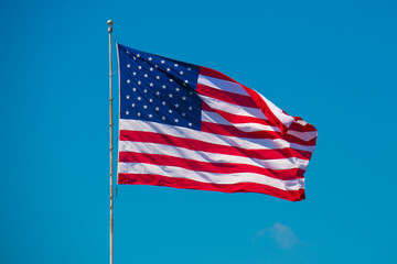 US American Flag waving in wind. Blue sky on background. Star striped patriotic symbol. United States of America. 4th of July Independence Day. 