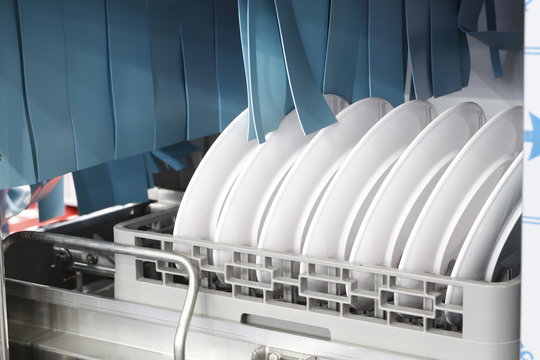 The automatic dishwasher with white clean dishes in basket .For restaurant.