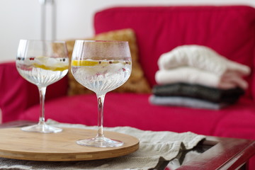 Gin and tonic with lemon and spices in crystal glass on the table in living room