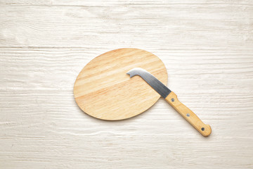 Cutting board with knife on white wooden background
