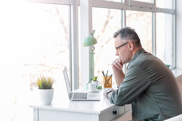 Mature man using laptop at home - obrazy, fototapety, plakaty