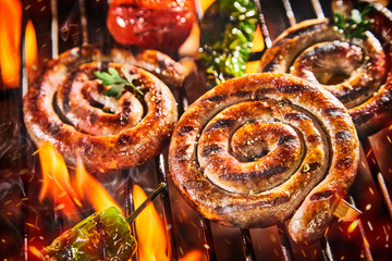 Close up on spicy coils of sausage grilling on BBQ - obrazy, fototapety, plakaty