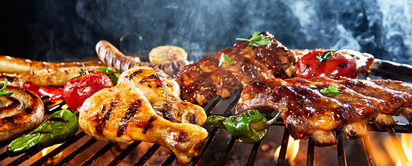 Assorted meat grilling over a BBQ outdoors - obrazy, fototapety, plakaty