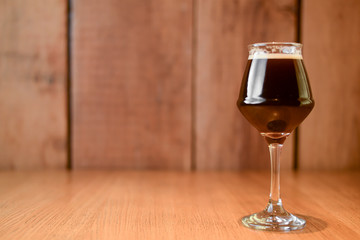 Glass of dark beer on light wooden background. Alcohol drink. Food photography concept, copy space.