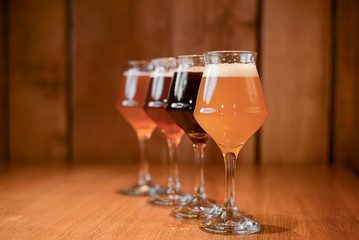 Three glasses with different beer on wooden table in a bar. Food photography concept, with copy space