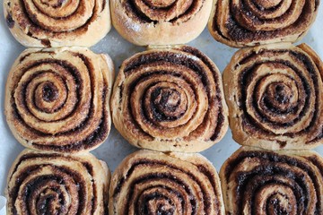 Fototapeta premium Freshly baked and tasty cinnamon rolls and a cup of black coffee. Kanelbullens dag 