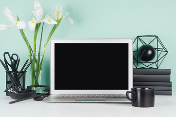 Modern workplace with blank computer display, black stationery, books, coffee cup, abstract atom...