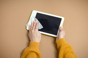 Woman cleans white tablet, gadget desinfection while virus. Home office while self-isolation,...
