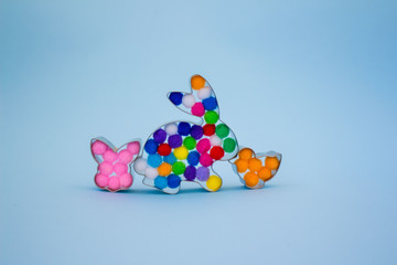 Rabbit bunny and bird shaped forms for gingerbread or cookies decorated with colorful balls inside on trendy blue background with copy space for your creative design. Easter concept