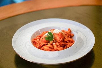 Macaroni pasta with bolognese sauce and parmesan cheese on a white plate on dark rustic wooden table.