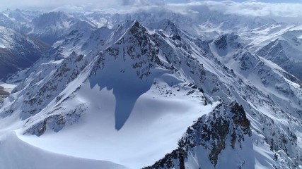Helicopter flight over incredible epic mountain landscape winter snow covered sharp peaks of many rocky volcanic slopes. Mountains tops. Fairy nature Scandinavia Himalayas Tibet. Cumulus clouds sunny. - Powered by Adobe