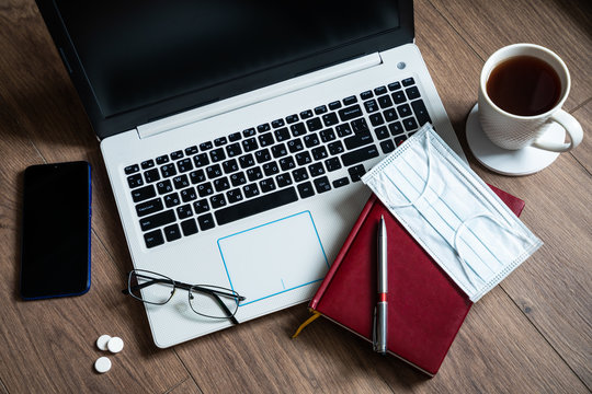 The concept of remote work at home during the coronavirus epidemic. Workplace with laptop, smartphone and notepad. Means of protection and hygiene