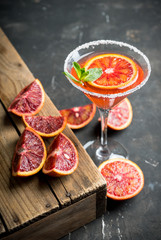 Red cocktail with bloody oranges in martini glass on the rustic background. Selective focus. Shallow depth of field.
