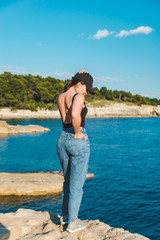 young pretty woman sitting on the cliff looking at sea