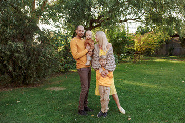 Obraz premium family in nature, summer or autumn, green grass trees in green leaves, a pond in nature, mom blonde in a yellow dress, dad, husband, older son and youngest son, two children, a large and happy family