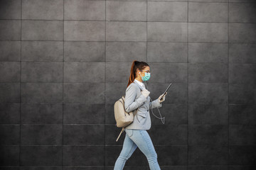 Young woman in protective suit with mask typing on tablet, prevent infection of Covid-19 virus...
