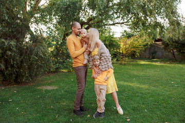 Obraz premium family in nature, summer or autumn, green grass trees in green leaves, a pond in nature, mom blonde in a yellow dress, dad, husband, older son and youngest son, two children, a large and happy family