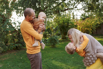 
family in nature, summer or autumn, green grass trees in green leaves, a pond in nature, mom blonde in a yellow dress, dad, husband, older son and youngest son, two children, a large and happy family