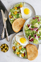 Serving breakfast for two fried eggs with fresh salad, top view