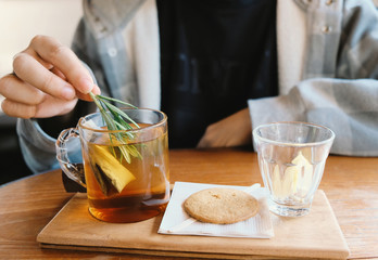 Close up young man hand putting rosemary into the hot tea for afternoon tea time break, relaxing and cozy at home