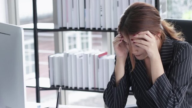 Young businesswoman feeling tired and stressed on computer. She sitting at the workplace