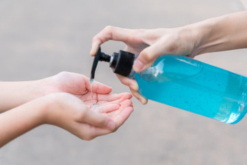 Fototapeta premium Coronavirus or COVID-19 pandemic prevention, Mother put hand sanitizer to hand daughter wash hands with Alcohol based hand sanitizer and , rubbing nails and fingers washing frequently .