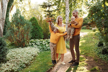 Naklejka na ściany i meble family in nature, summer or autumn, green grass trees in green leaves, a pond in nature, mom blonde in a yellow dress, dad, husband, older son and youngest son, two children, a large and happy family