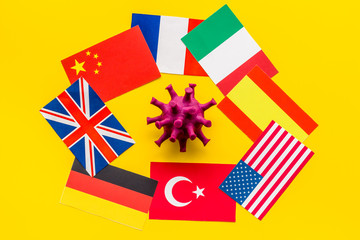 Concept of Corona virus Covid-19 epidemic with flags on yellow background top-down