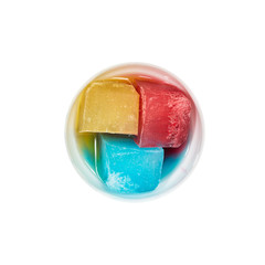 Top view of bowl with colorful ice melting on white