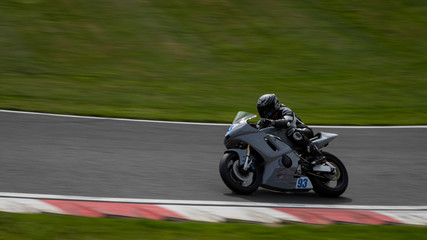 A panning shot of a grey racing bike speeding round corners on a racetrack.