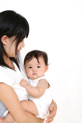 お母さんに抱かれカメラ目線の笑顔の赤ちゃん。