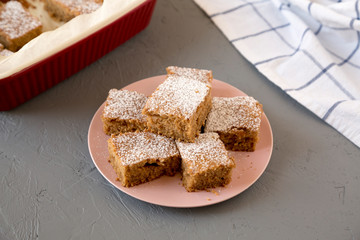 Homemade Tasty Applesauce Cake on a pink plate on a gray background, side view.