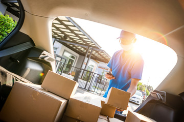 Asian delivery man wearing mask protect covid-19 virus and stocktaking checklist with amount of parcels, part-time job service.