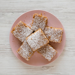 Homemade Tasty Applesauce Cake on a pink plate on a white wooden surface, top view. Flat lay, overhead, from above.