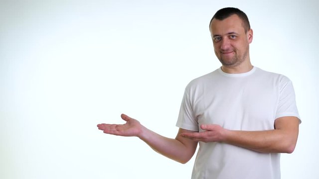 Young man in white t-shirt pointing rightwards against white background. Young boy introduce product, pointing right blank copy space