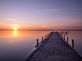 Fototapeta na wymiar Steg im Wasser beim Sonnenuntergang