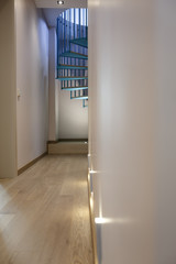 Spiral staircase, forged blue handrail and wooden steps in modern home. View from the corridor.