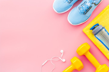 Fitness equipment. Sneakers, dumbbells, headphones on pink background top view copy space